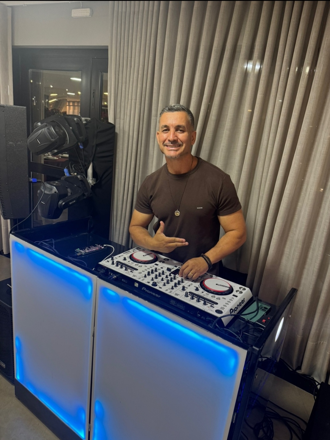 DJ operando mesa de som com iluminação profissional ao fundo