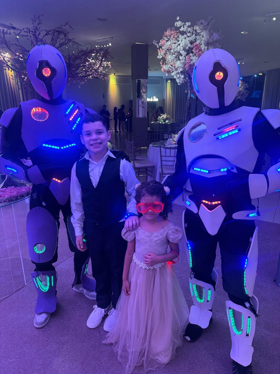 Dois robôs de LED com crianças em festa decorada