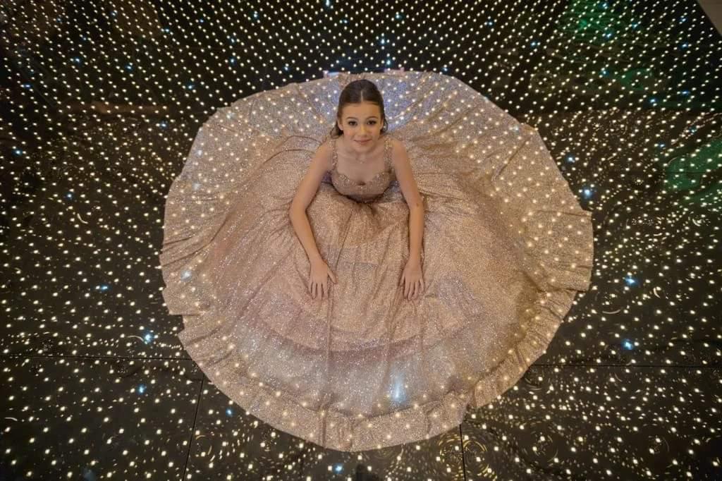 Debutante com vestido rodado sobre pista iluminada